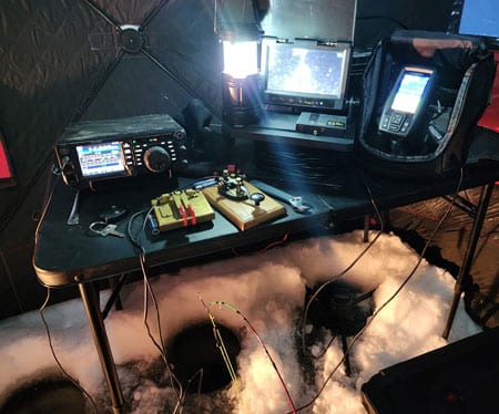 Ham gear set up on table in a tent on ice with holes cut for fishing