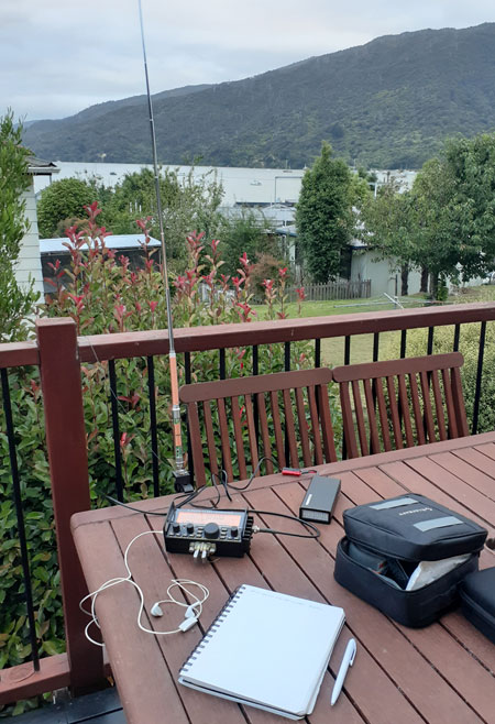 Elecraft KX2 and whip antenna set up on a table on a deck