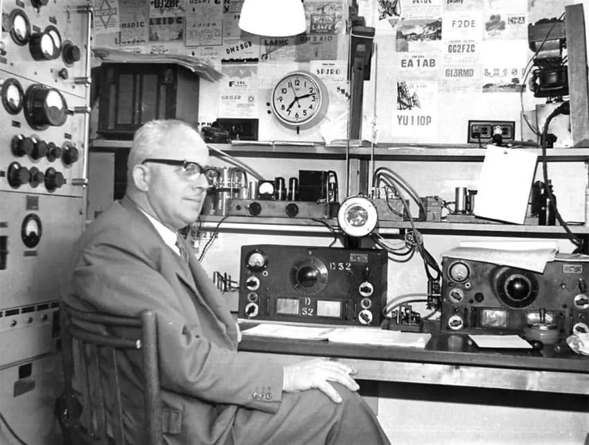 man sitting with ham radio equipment including HRO receiver and large homebrew transmitter