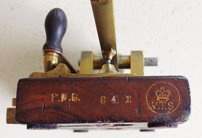 Close-up of end of Morse key base, engraved PMG 842 and the VTS badge with crown