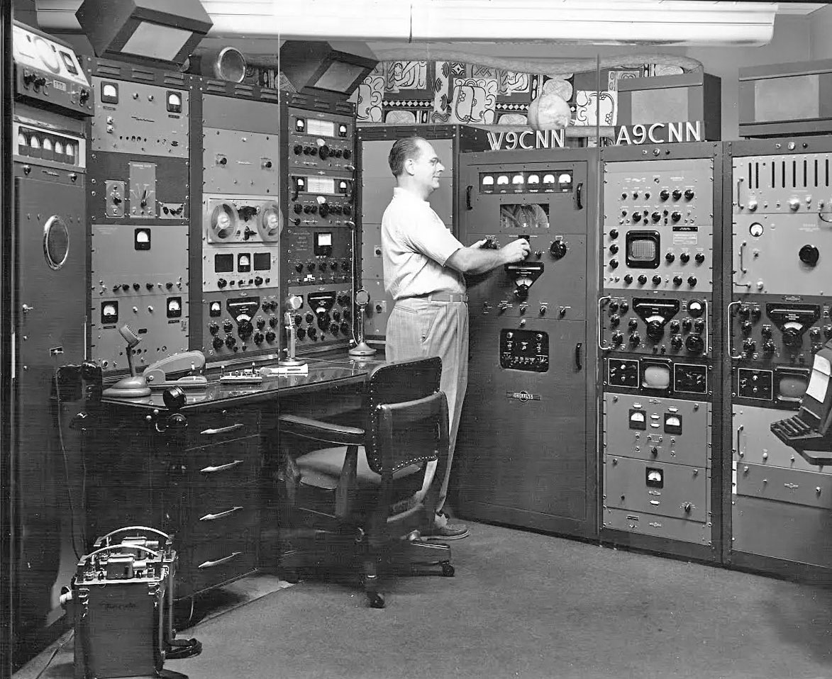 Ham adjusting his Collins KW-1 transmitter in a very well-equipped ham shack